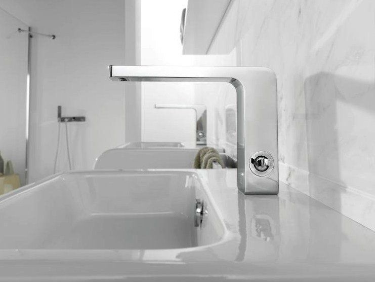 Lavabo da bagno moderno di colore bianco con rubinetto cromato e specchio a parete sopra la vasca.