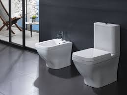 Due moderni WC bianchi su un pavimento grigio in uno showroom di bagni.