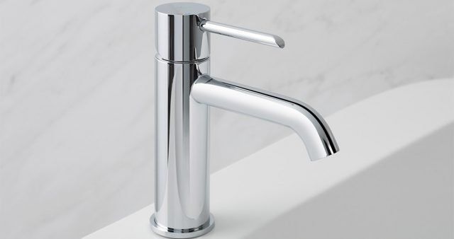 Rubinetto da bagno cromato su lavabo bianco con alzatina in marmo.