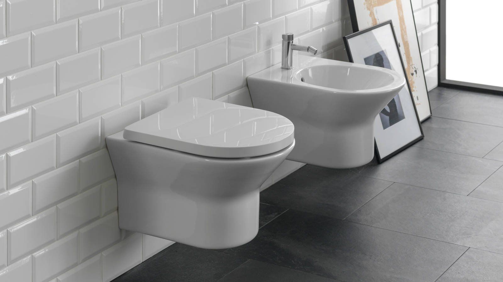 Due WC sospesi bianchi in uno showroom di bagni moderni piastrellati.