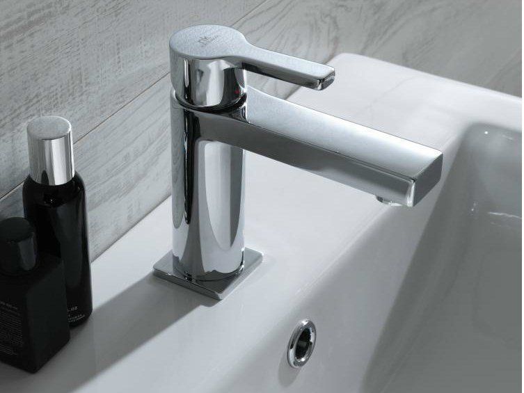 Rubinetto da bagno cromato su un lavabo bianco con un dispenser di sapone nero accanto.