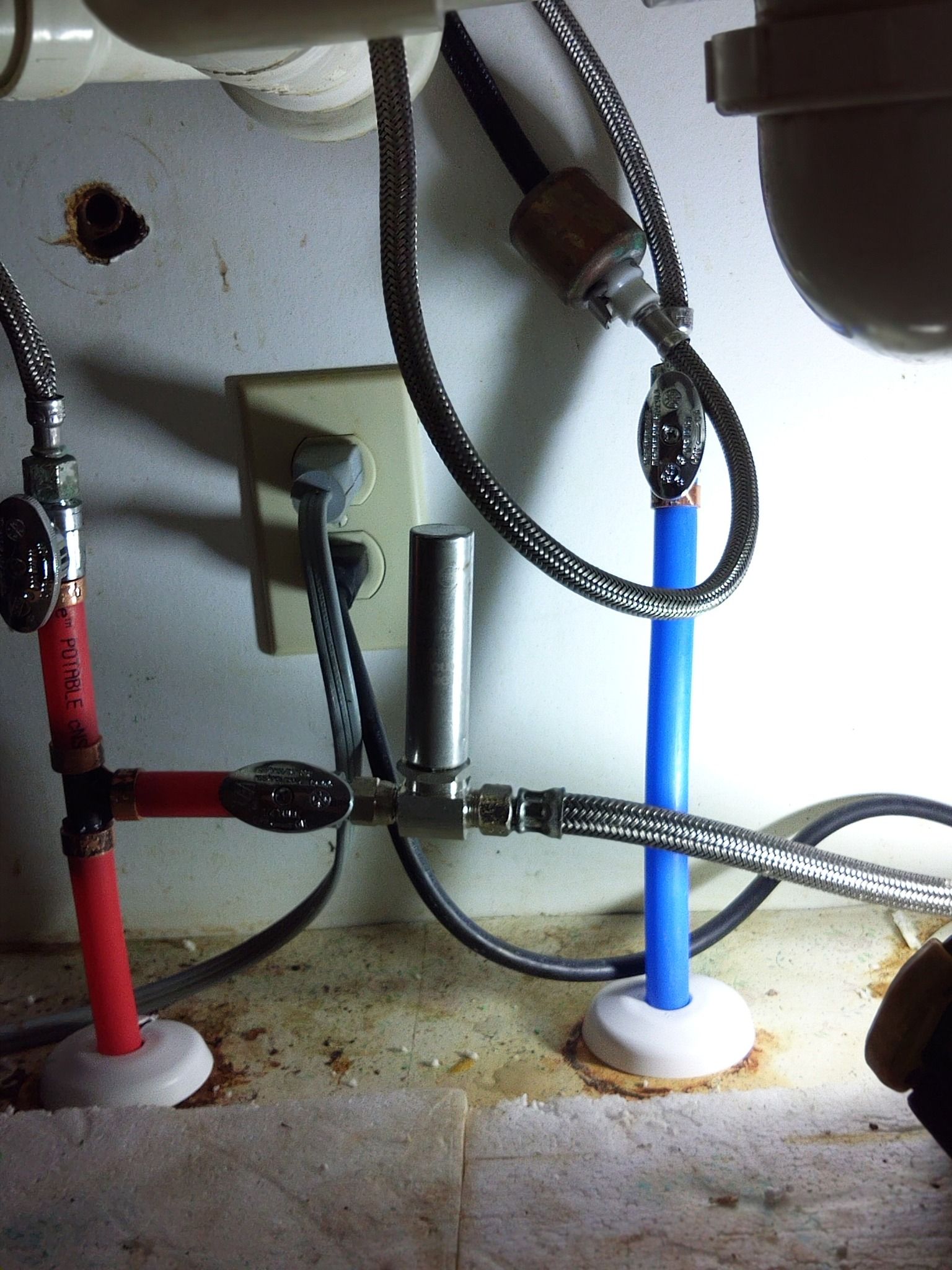 A close up of a sink with red and blue pipes