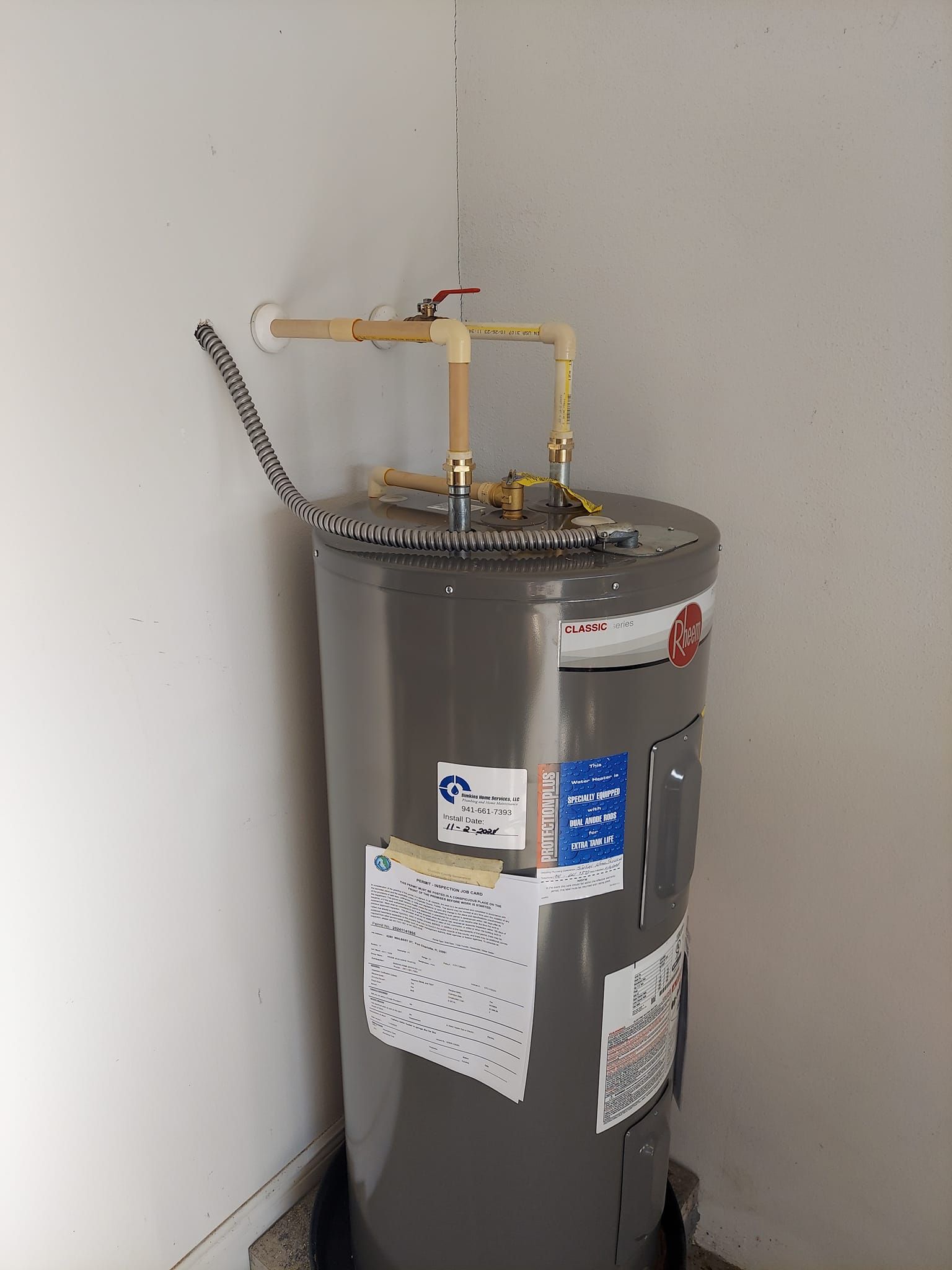 A stainless steel water heater is sitting in a corner of a room.
