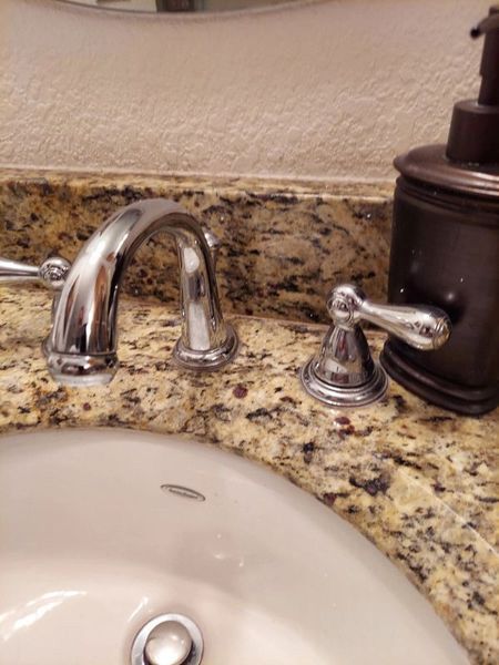 A bathroom sink with a soap dispenser next to it
