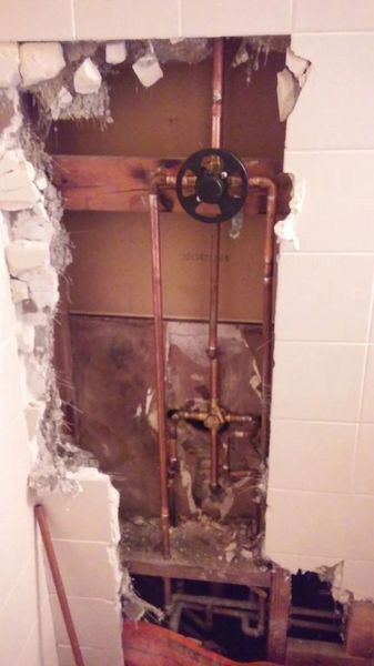 A hole in a wall with pipes coming out of it.