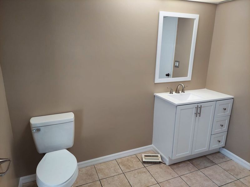 A bathroom with a toilet , sink and mirror