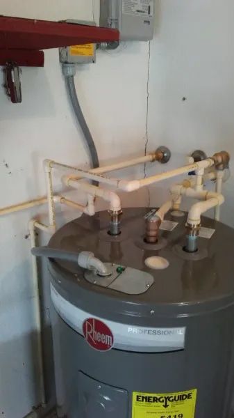 A water heater is sitting in a room next to a wall.