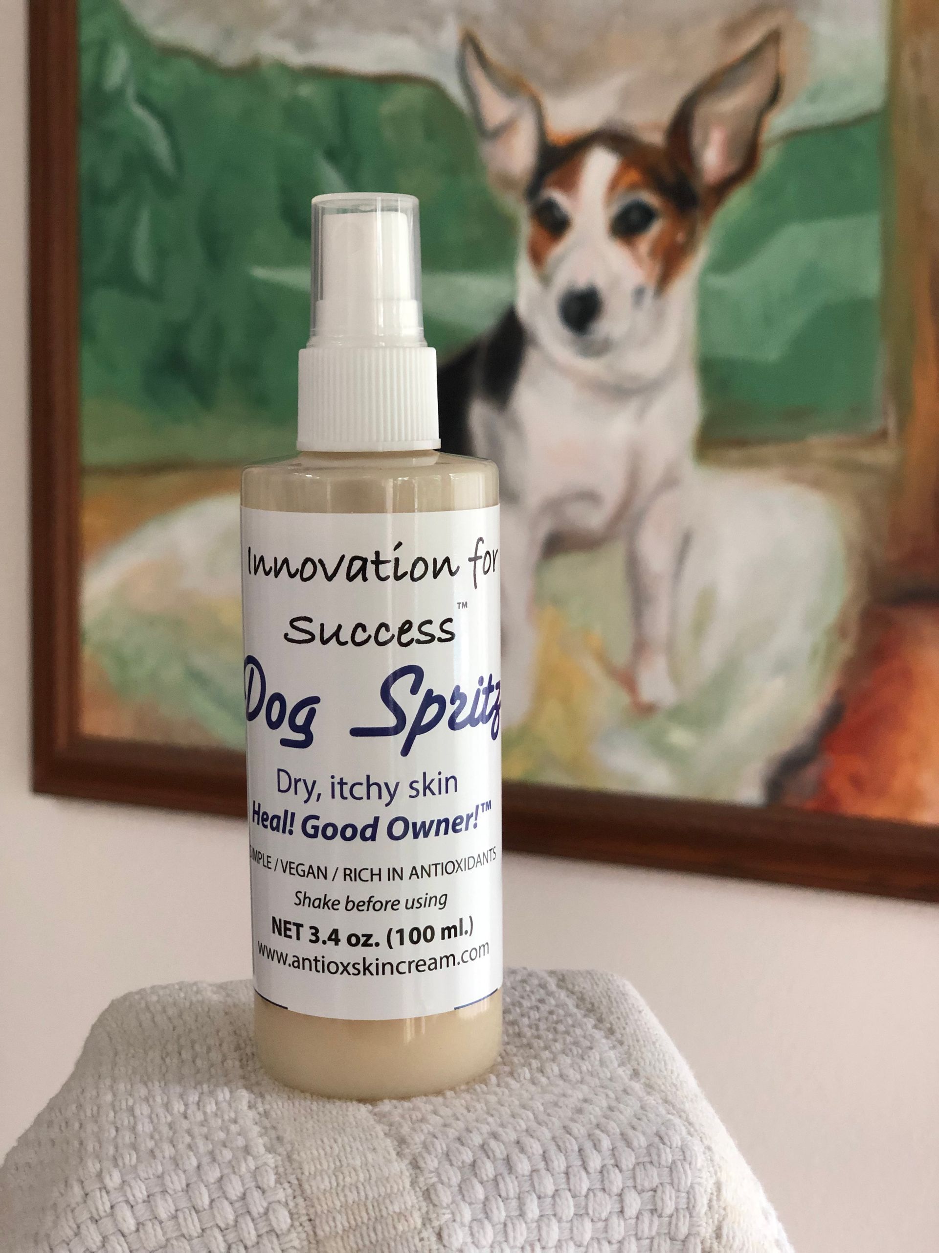 A bottle of dog spray is sitting on a towel in front of a picture of a dog