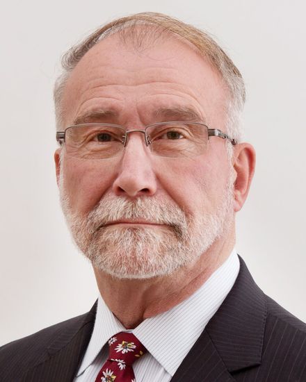 A man with a beard and glasses is wearing a suit and tie