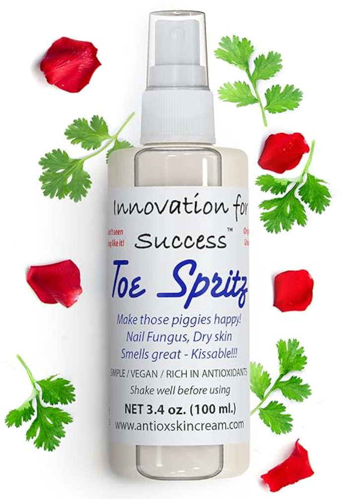 A bottle of toe spritz is surrounded by rose petals and parsley