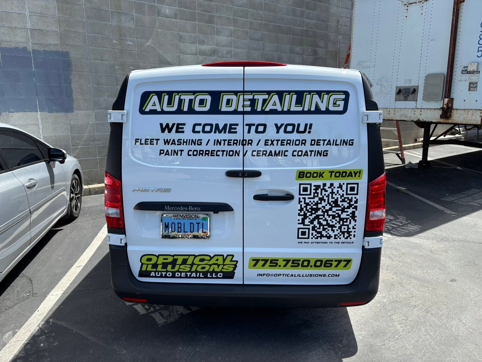 Auto detailing van with large rear advertising sign parked in a lot.
