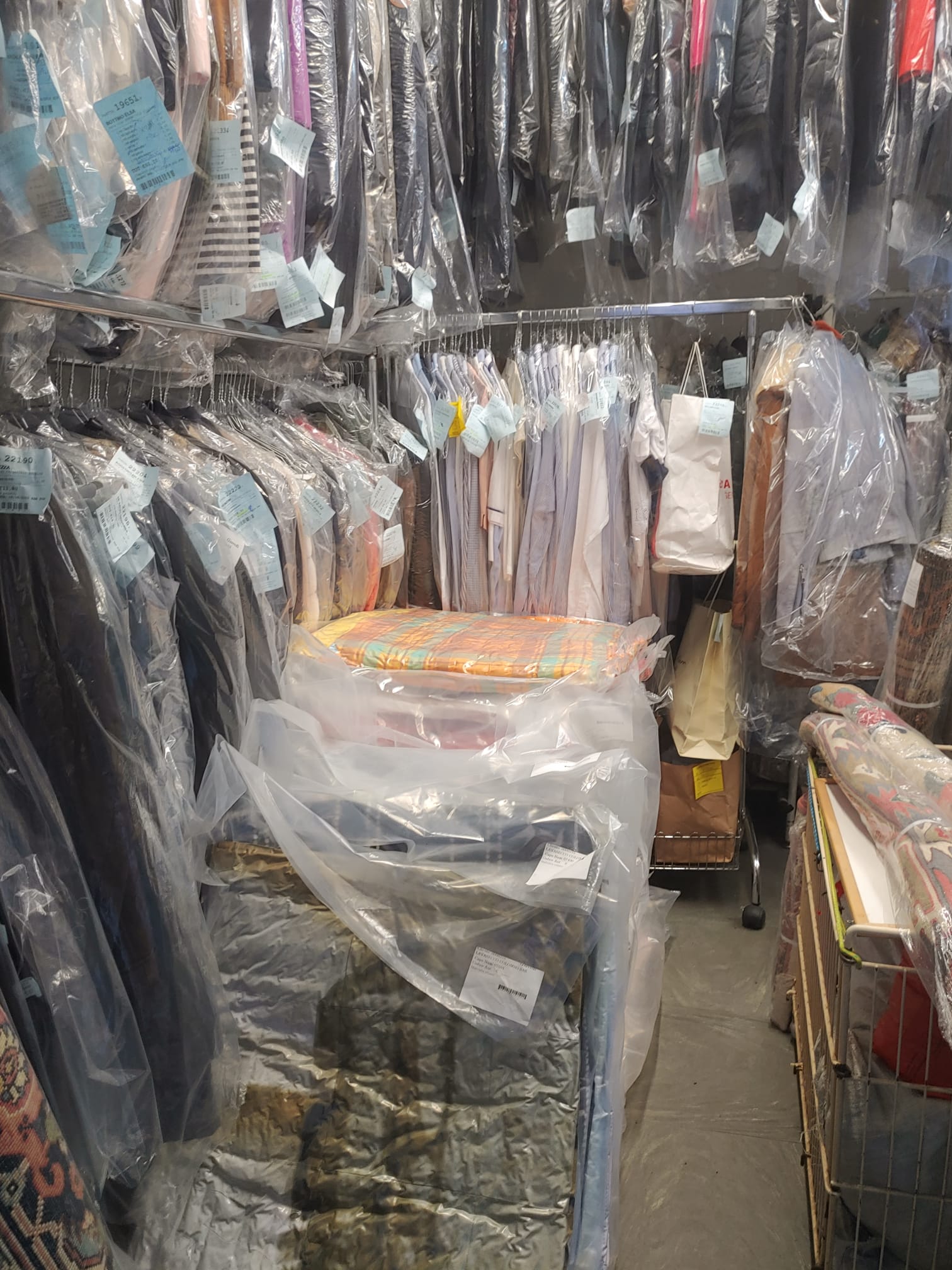 Abiti avvolti nella plastica appesi in una lavanderia a secco.
