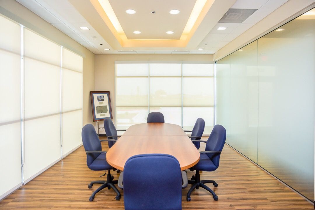 Modern conference room with oval table, blue chairs, and frosted glass walls