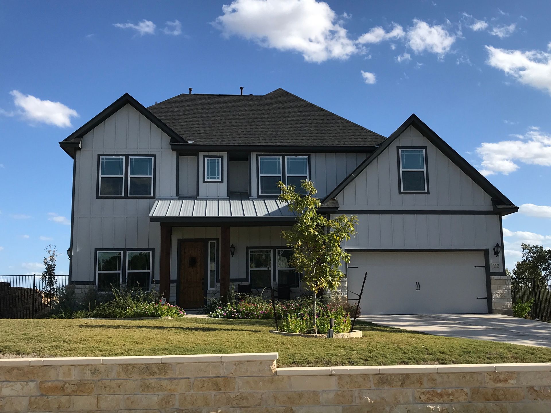 Two-story gray house with a garage and balcony under a blue sky