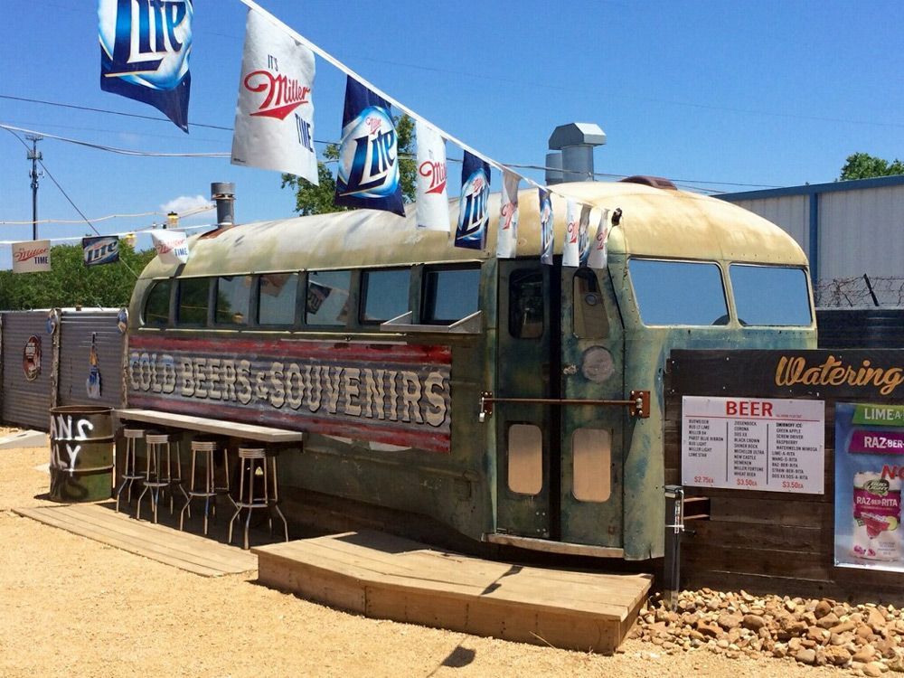 Vintage bus converted into a diner with outdoor stools and flags in a sunny roadside setting