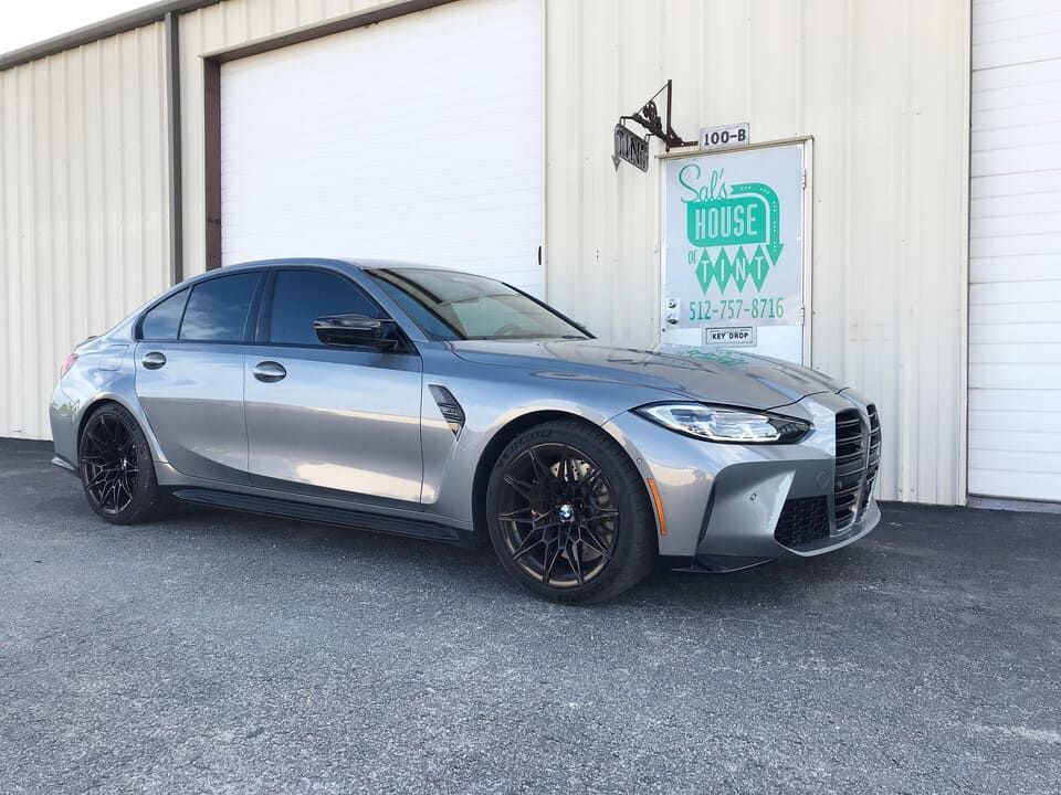 Silver BMW sedan parked outside a warehouse with a white roll-up door