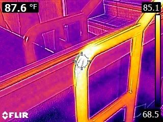 Thermal image of a bright hot handrail with a cooler purple staircase and railings around it