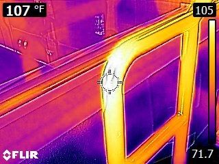 Thermal view of a car door and window, showing hot yellow-orange surfaces and cooler purple surroundings.
