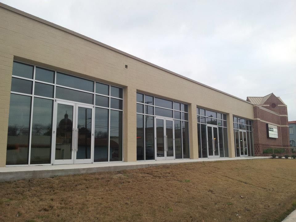 Modern building exterior with large glass windows and a brick entrance on a grassy slope