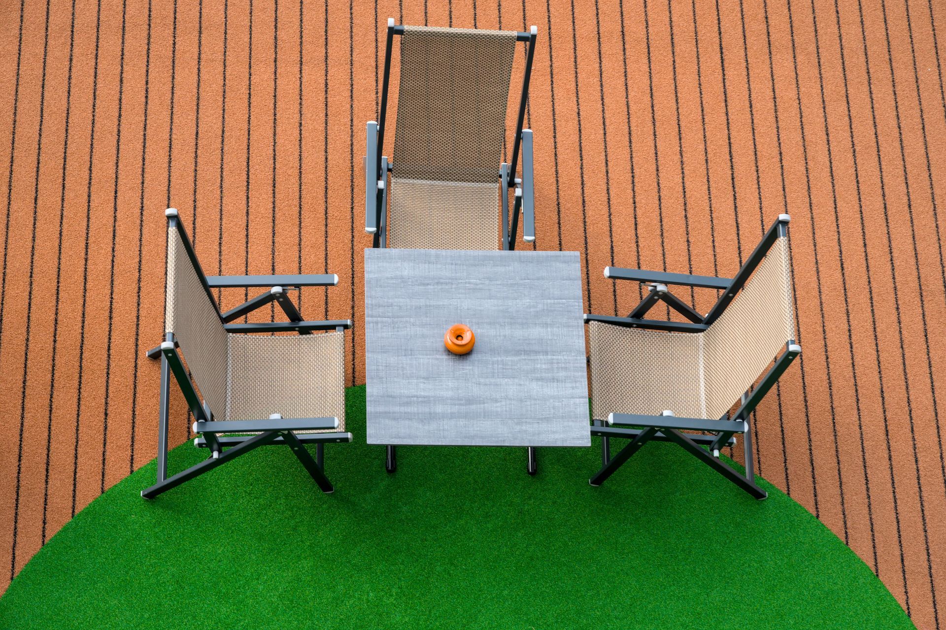 Outdoor patio table with four chairs on a green lawn against a brick wall