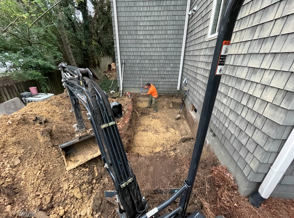 Basement with white wrapped walls and metal supports, leading to an open door and a yard.