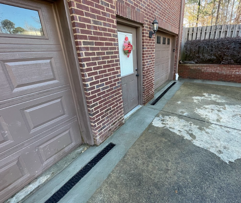 Basement with white wrapped walls and metal supports, leading to an open door and a yard.
