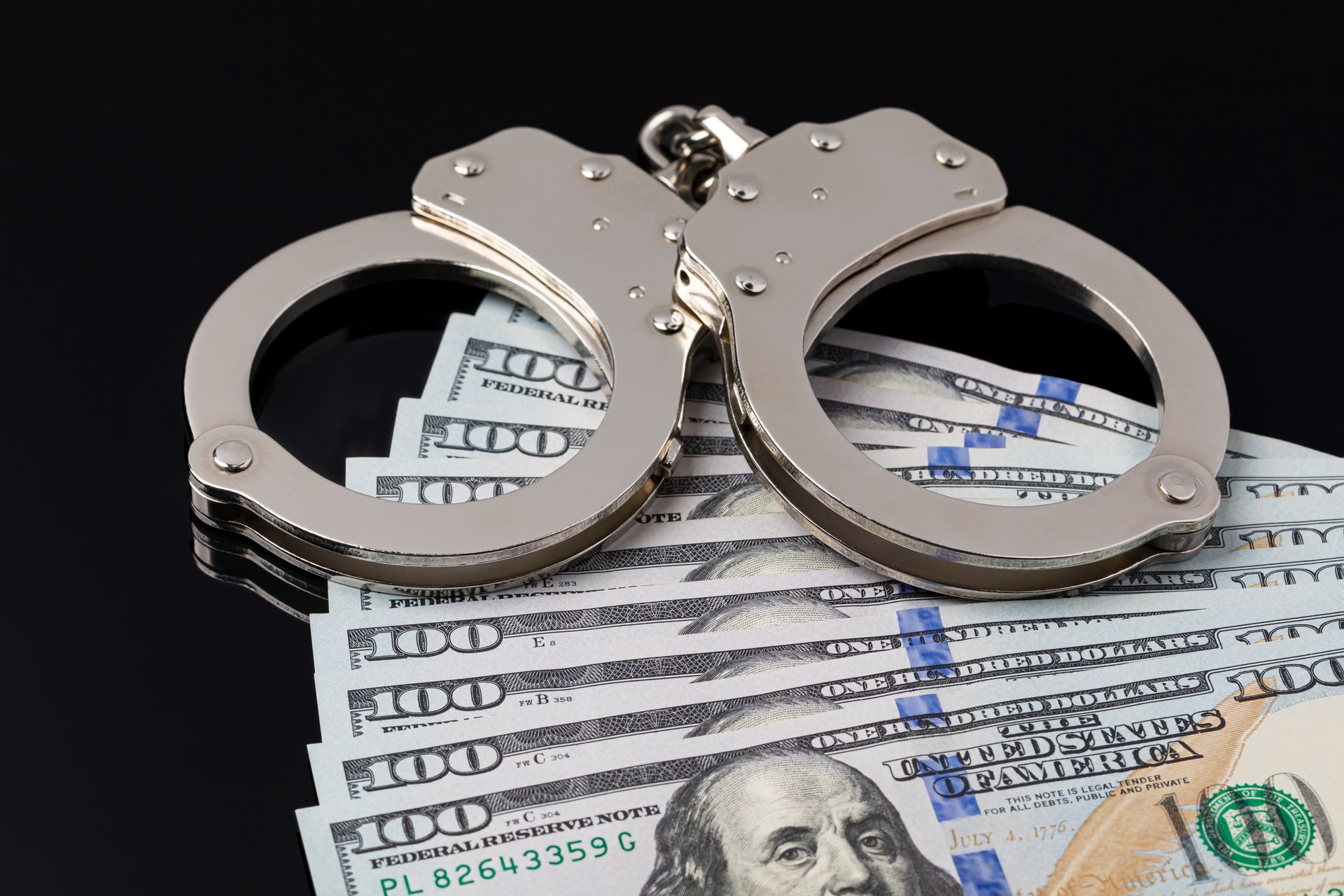 Bail bond concept showing handcuffs placed over cash collateral.