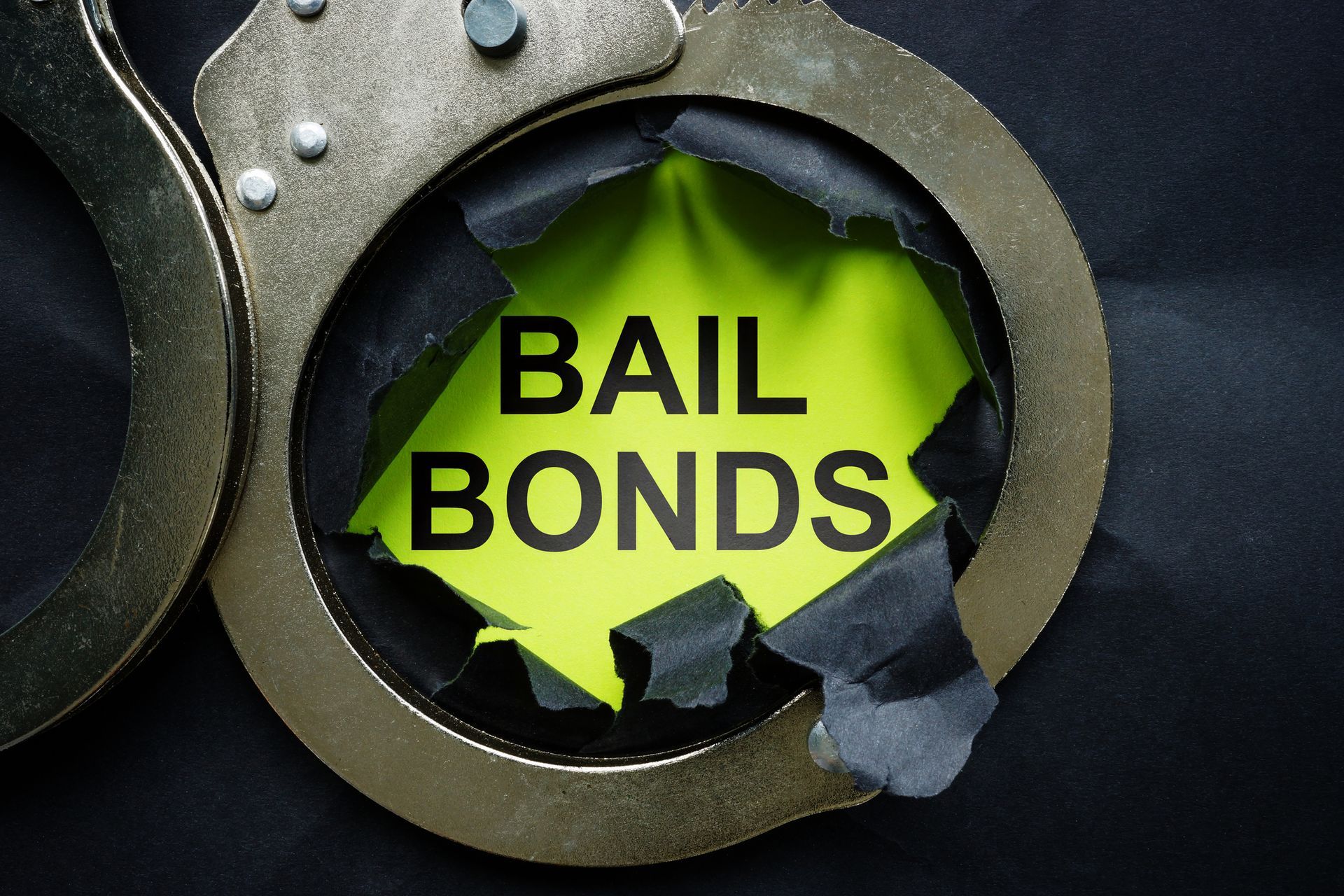 Bail bonds text exposed through ripped paper inside metal handcuffs.