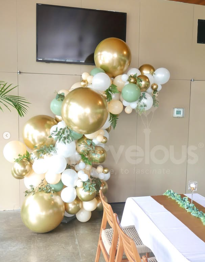 A bunch of gold and white balloons are hanging from the ceiling