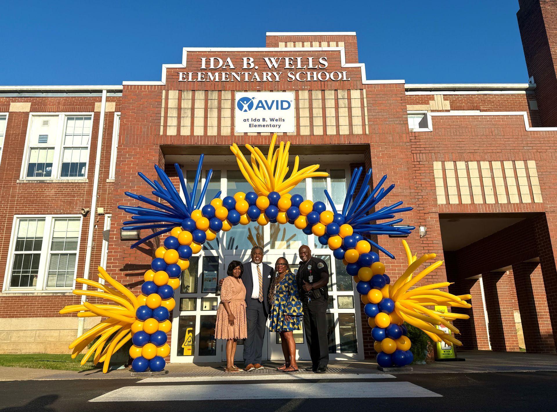 yellow and blue balloon arch outside at school