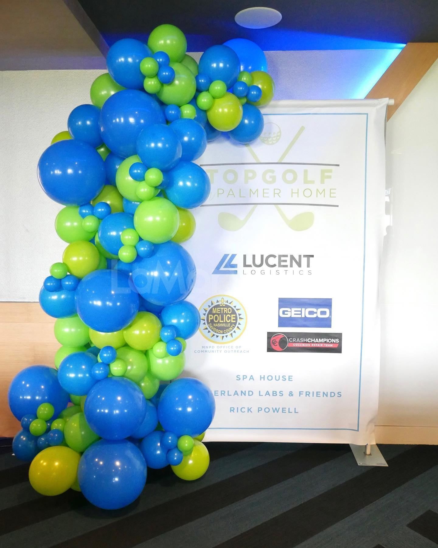 Blue and green balloons are displayed in front of a sign that says lucent