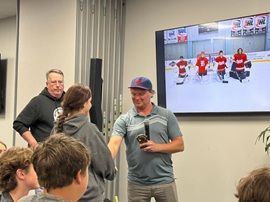 People gathered in a room watching a hockey game on a wall-mounted TV.