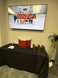 Office display with a wall-mounted hockey team photo above a black table with gifts and snacks.