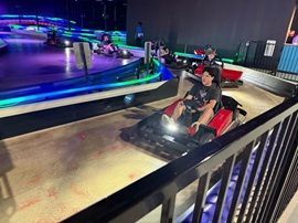 Two people driving red go-karts on an indoor neon-lit track