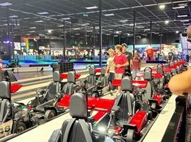 Indoor go-kart track with red and black karts and a few people standing nearby