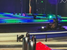 Go-kart racing at night with neon blue and green track lights