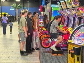 People playing colorful arcade motorcycle games in a bright game room