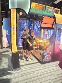 Two people posing inside a colorful arcade game booth with bright neon lights