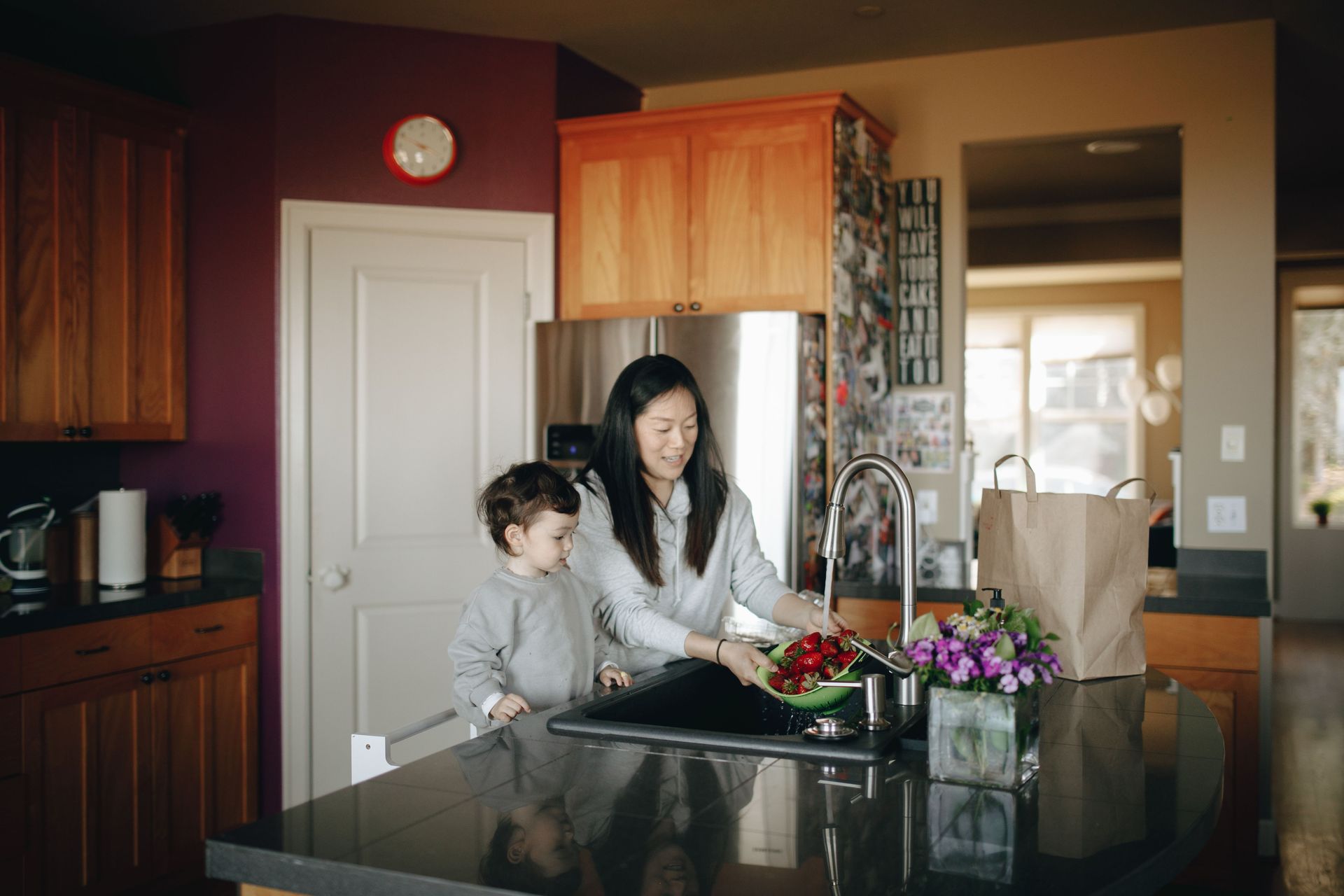 Woman and child preparing food at a kitchen island with flowers and groceries