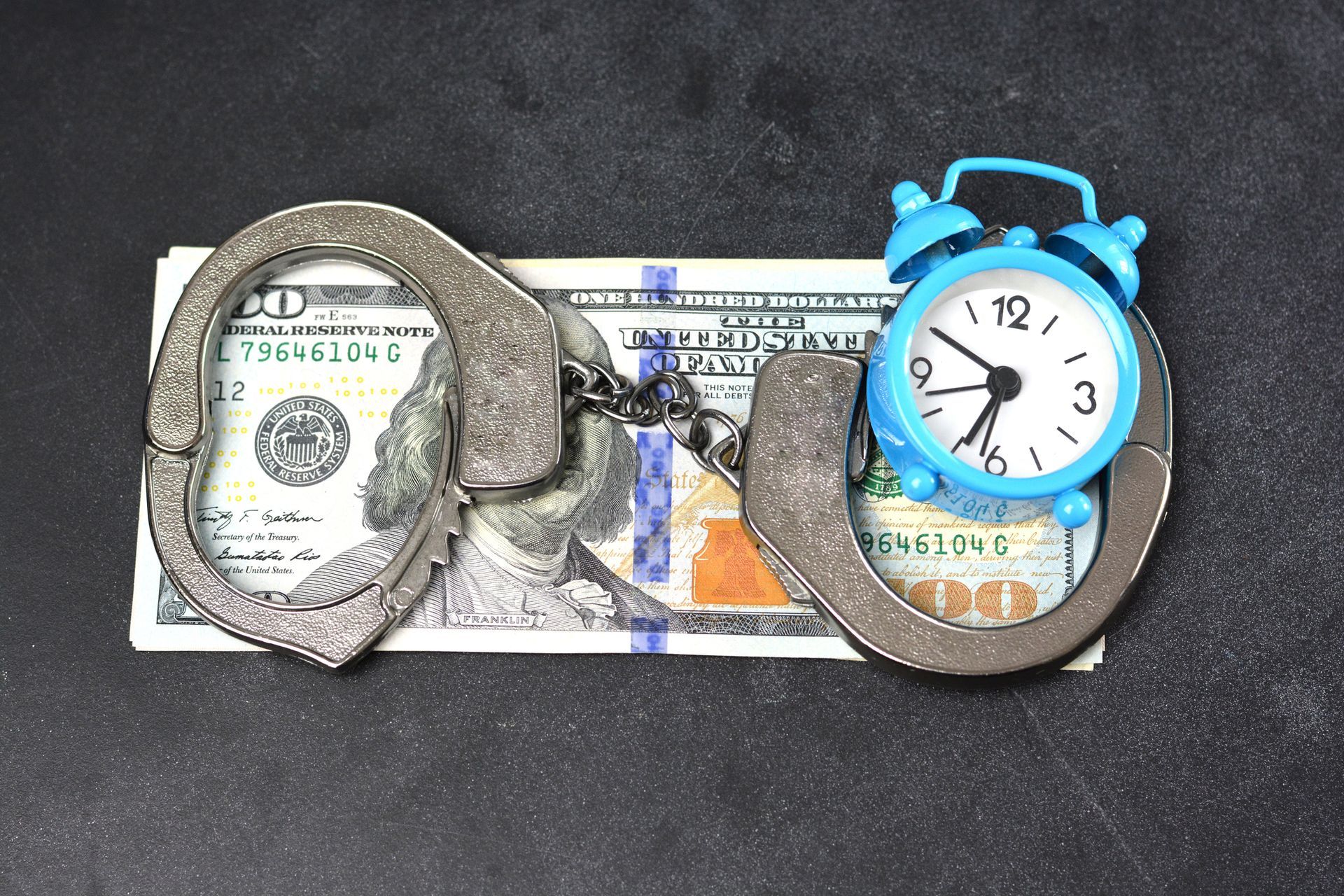 Handcuffs with cash and clock representing urgency for 24/7 bail bonds in Leeds, AL by AAA Alabama R