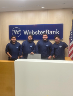A group of men standing in front of a webster bank sign