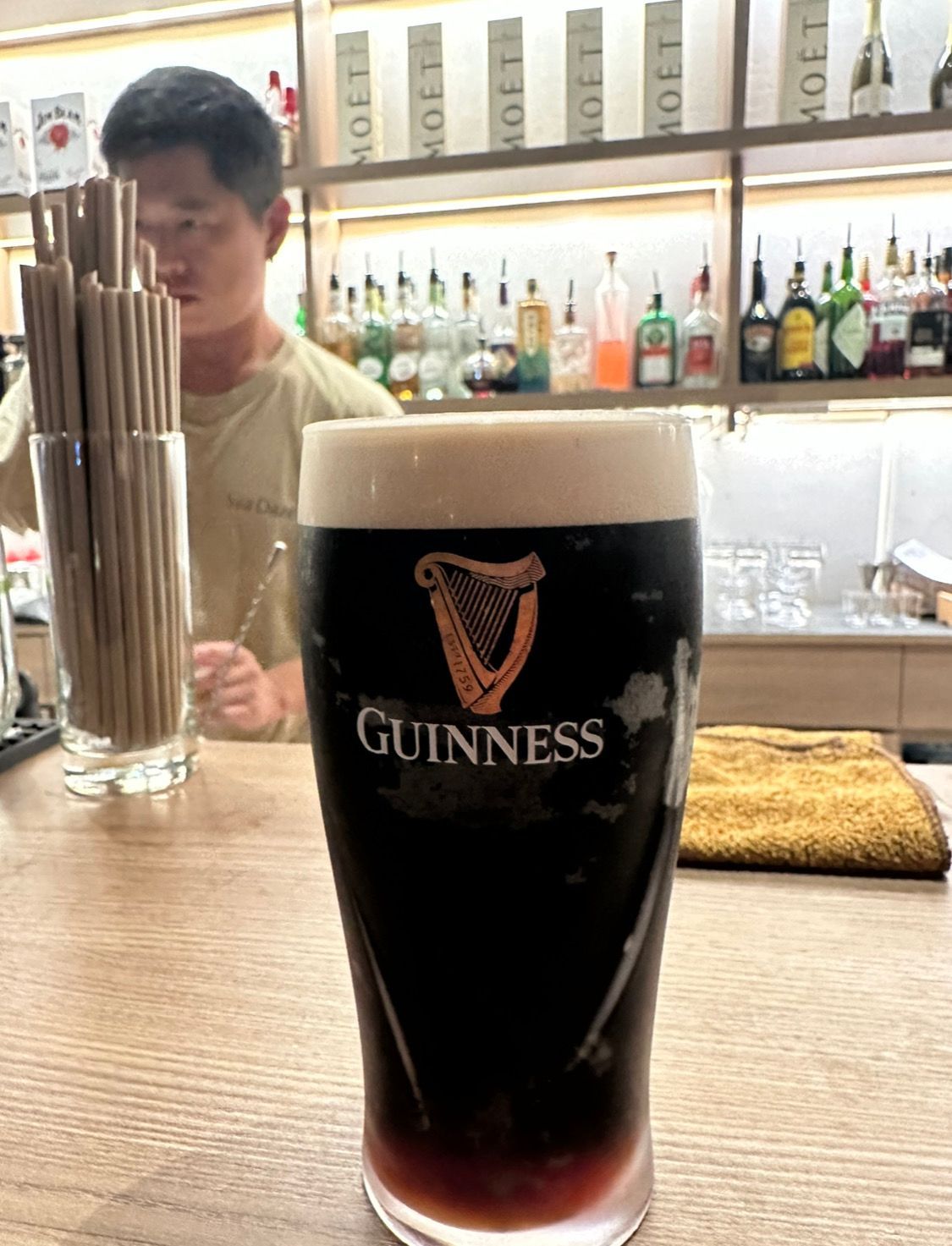 A glass of guinness beer is sitting on a bar counter.
