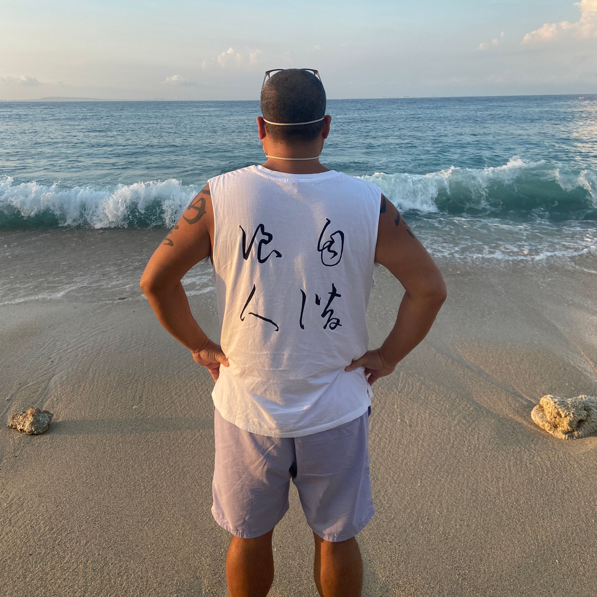 A man standing on a beach with chinese writing on his back