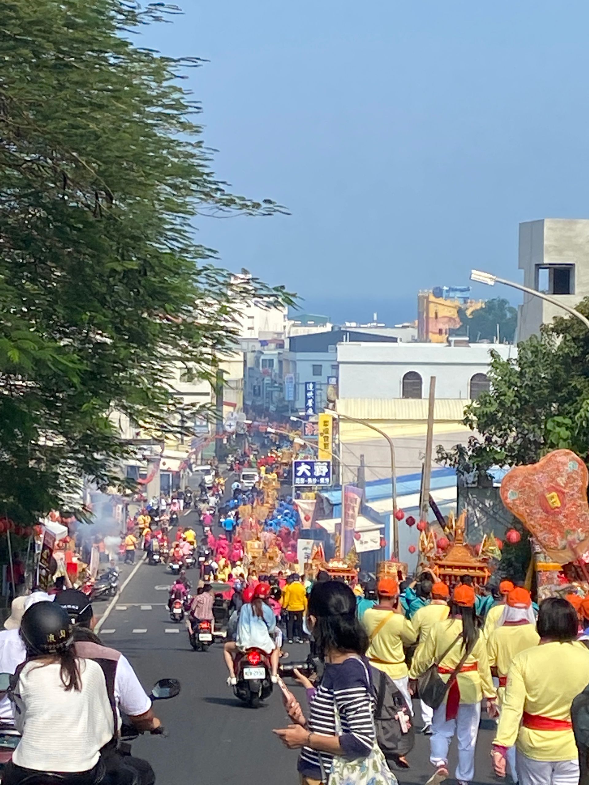A crowd of people are walking down a busy street.