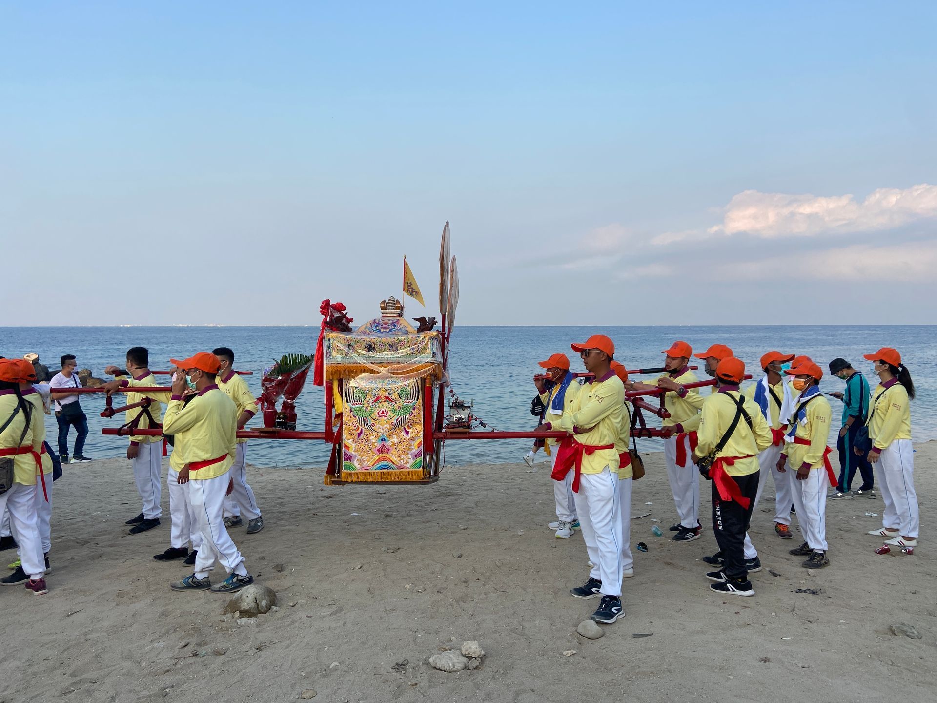 A group of people are standing on a beach holding a wagon.