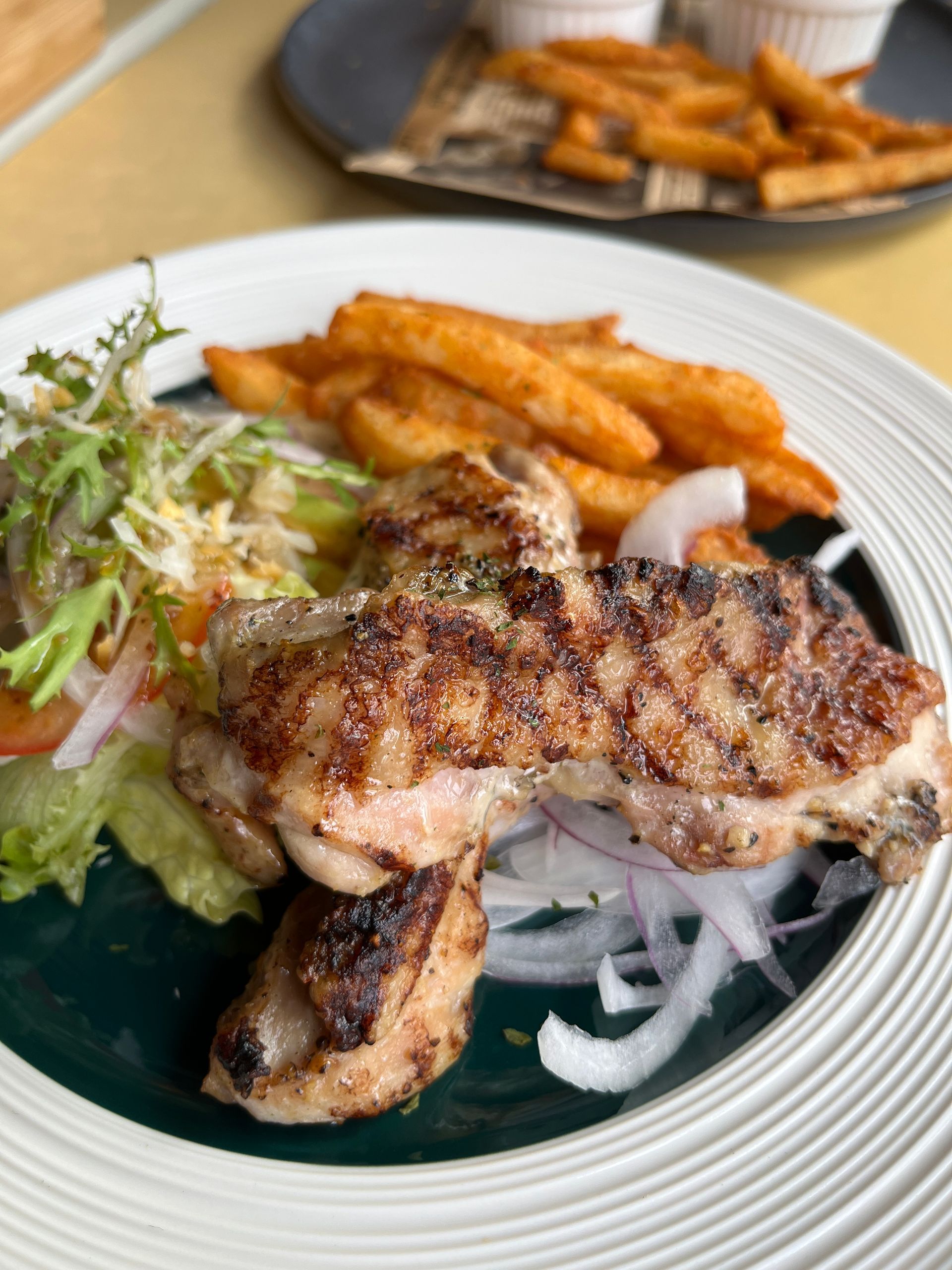 A plate of food with chicken and french fries on a table.