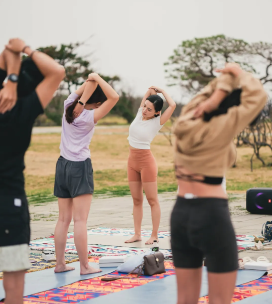 A couple of people are laying on a yoga mat in a field.