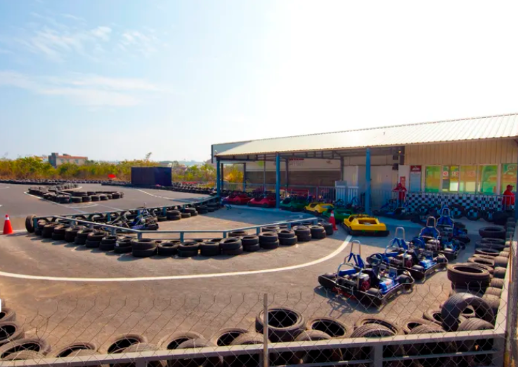 A go kart track with lots of tires and a building in the background.