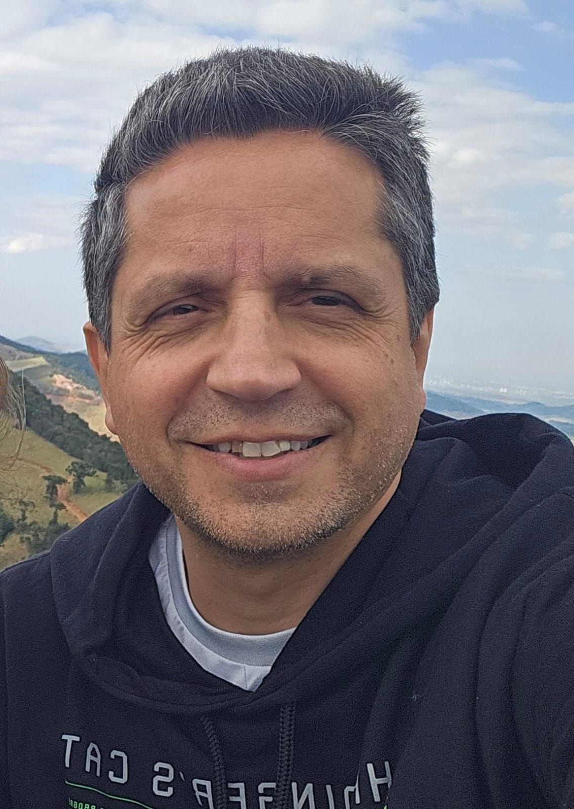 Um homem vestindo uma camisa azul e amarela está sorrindo para a câmera