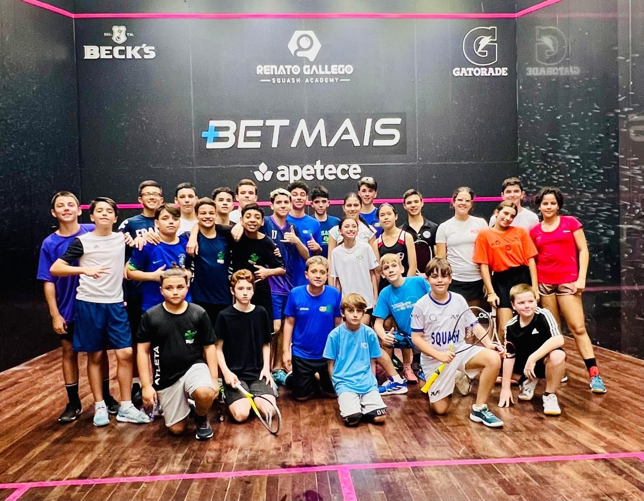 Um grupo de jovens está posando para uma foto em uma quadra de tênis.